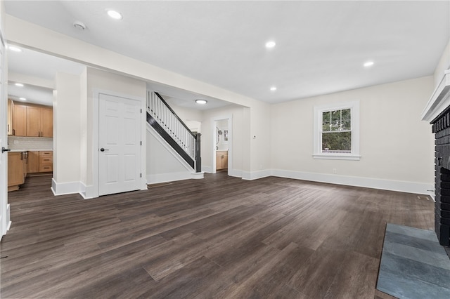 unfurnished living room featuring dark wood-type flooring and a brick fireplace