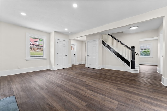 unfurnished living room with dark wood-type flooring and a wealth of natural light