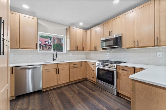 kitchen with stainless steel appliances, sink, decorative backsplash, light brown cabinetry, and dark wood-type flooring