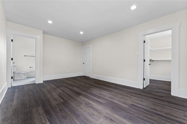 unfurnished bedroom with ensuite bathroom, dark hardwood / wood-style floors, a walk in closet, and a closet