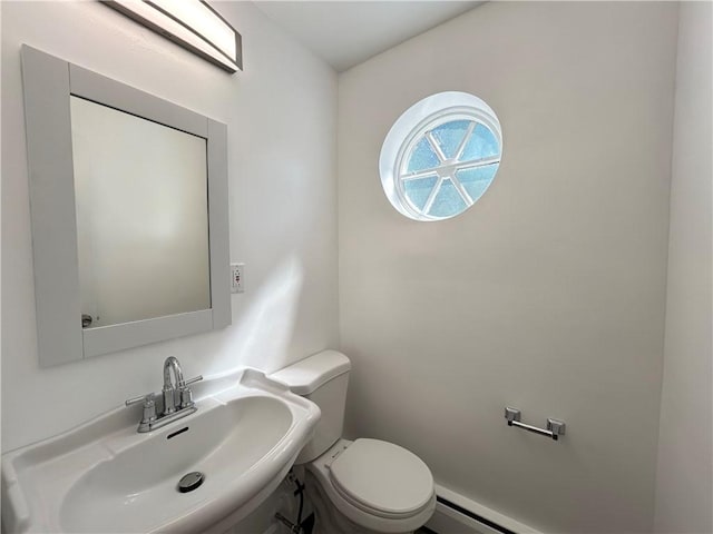 bathroom featuring toilet, a baseboard heating unit, and sink