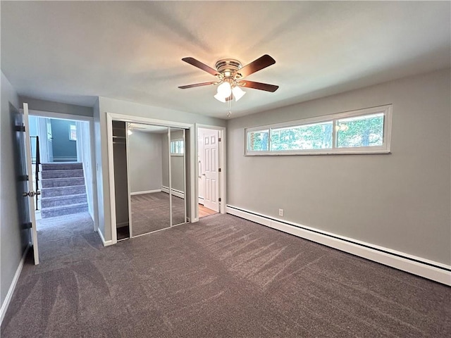 unfurnished bedroom featuring ceiling fan, a baseboard heating unit, a closet, and dark colored carpet