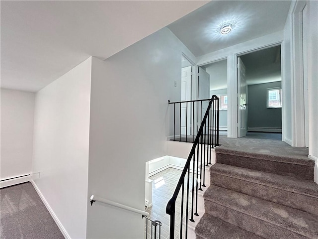 stairway with carpet floors and a baseboard heating unit