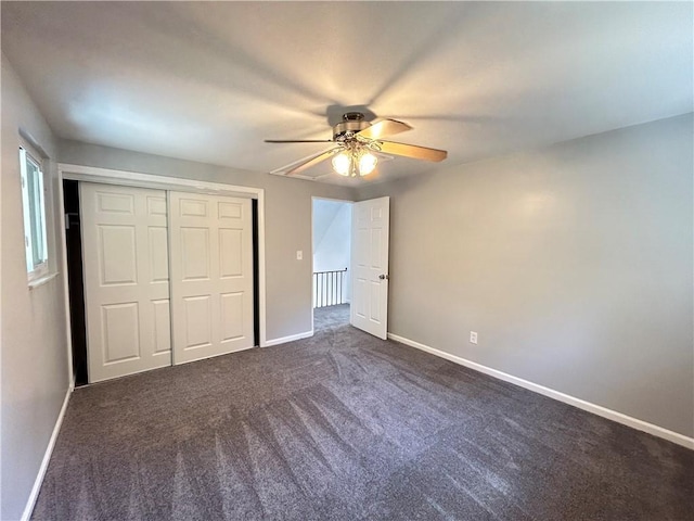 unfurnished bedroom with ceiling fan, dark carpet, and a closet