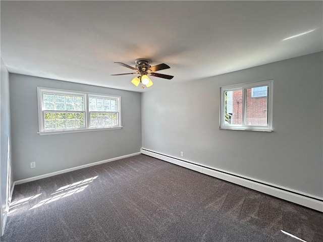 spare room with ceiling fan, baseboard heating, dark carpet, and plenty of natural light