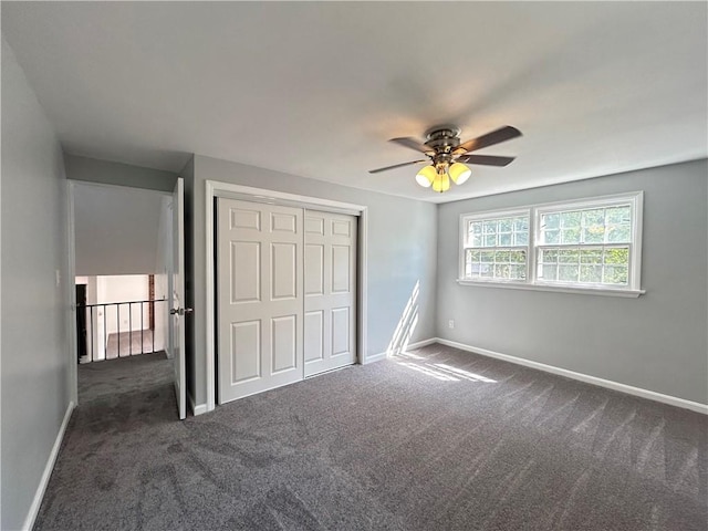 unfurnished bedroom featuring ceiling fan, a closet, and dark carpet