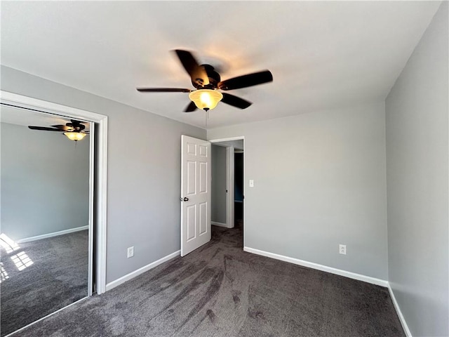 unfurnished bedroom with ceiling fan, a closet, and dark carpet