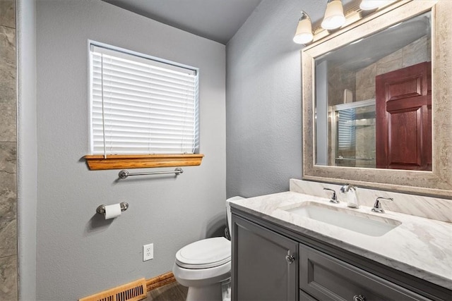 bathroom with toilet, vanity, and a shower with door