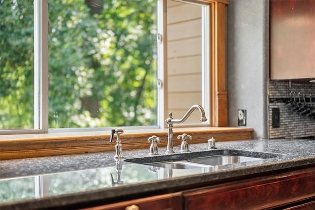 room details featuring dark stone countertops, backsplash, and sink