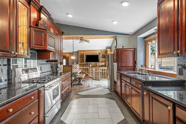 kitchen featuring ceiling fan, vaulted ceiling, dark tile patterned flooring, sink, and stainless steel appliances