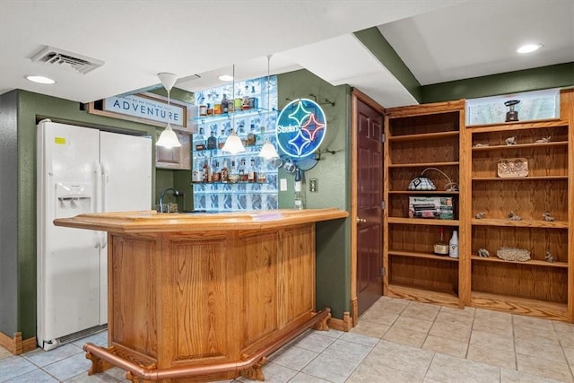 bar featuring light tile patterned floors and white refrigerator with ice dispenser