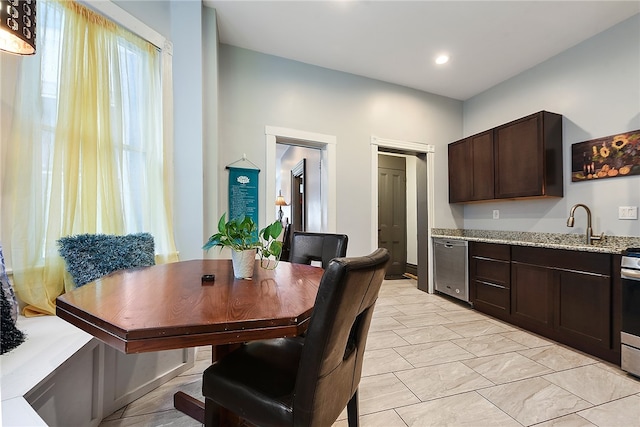 kitchen with appliances with stainless steel finishes, dark brown cabinets, light stone counters, and light tile patterned floors