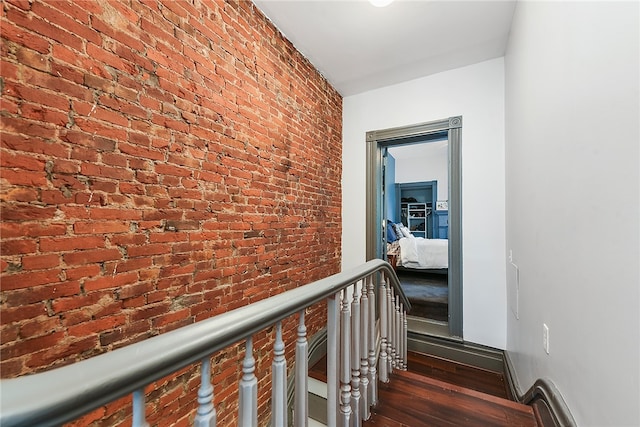 hallway with brick wall and dark hardwood / wood-style flooring