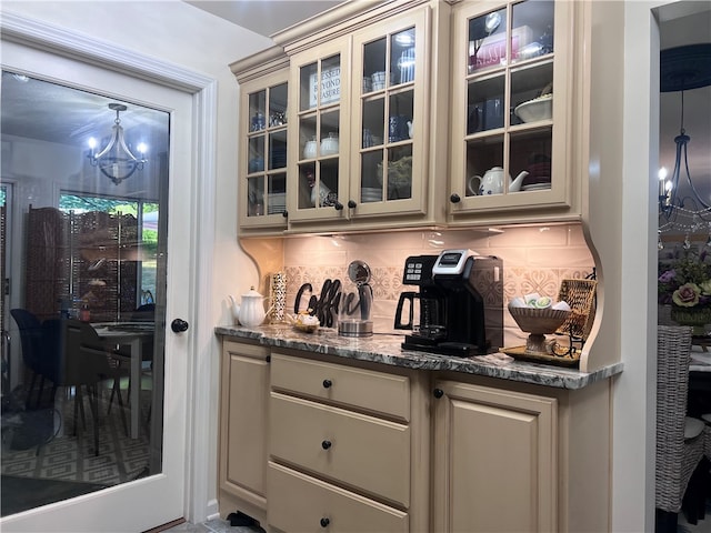 bar with dark stone countertops, a chandelier, decorative backsplash, and hanging light fixtures