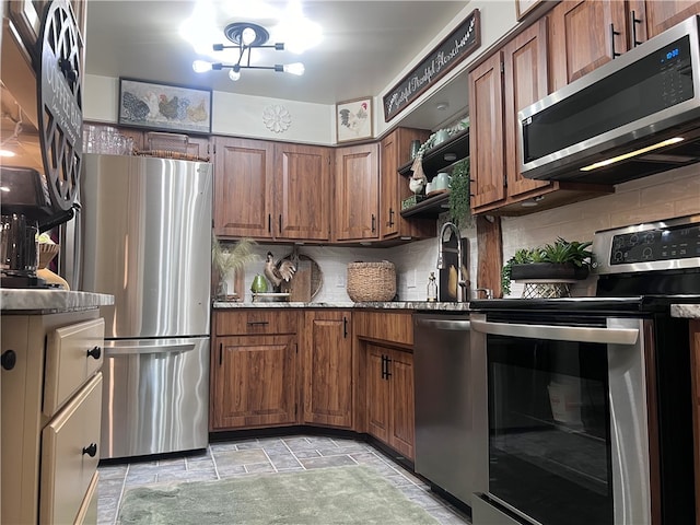 kitchen featuring stainless steel appliances, sink, light stone counters, and backsplash