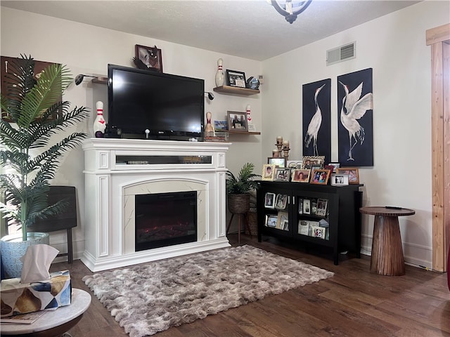 living room with a high end fireplace and dark hardwood / wood-style flooring