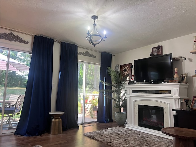 living room featuring a premium fireplace, wood-type flooring, a textured ceiling, and a chandelier