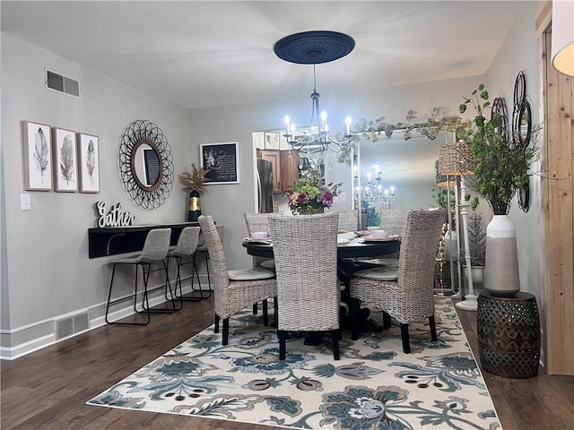 dining area featuring dark wood-type flooring and an inviting chandelier