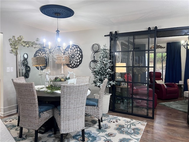 dining space featuring a barn door, wood-type flooring, and a chandelier