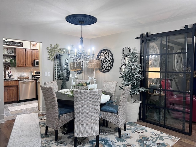 dining room featuring a barn door, hardwood / wood-style flooring, and a chandelier