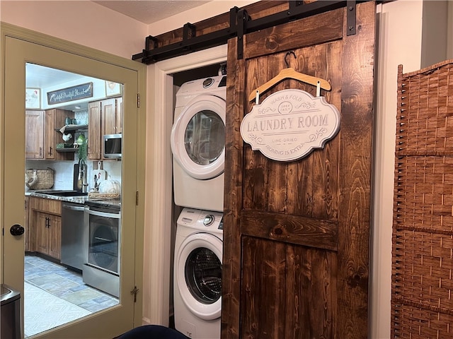 washroom featuring stacked washer and clothes dryer and a barn door