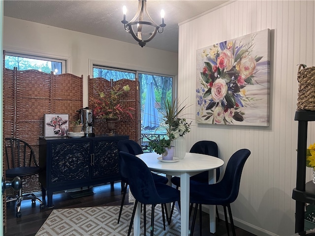 dining space featuring dark wood-type flooring, a textured ceiling, and a notable chandelier