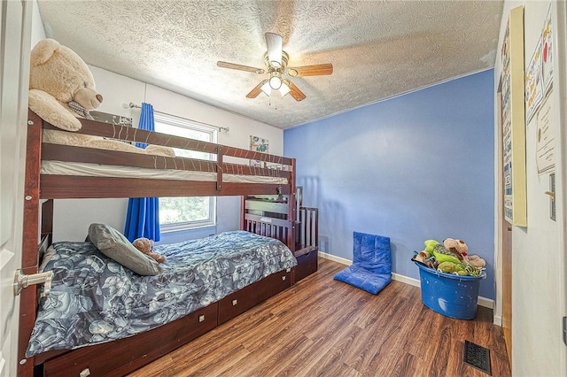 bedroom with visible vents, ceiling fan, a textured ceiling, wood finished floors, and baseboards