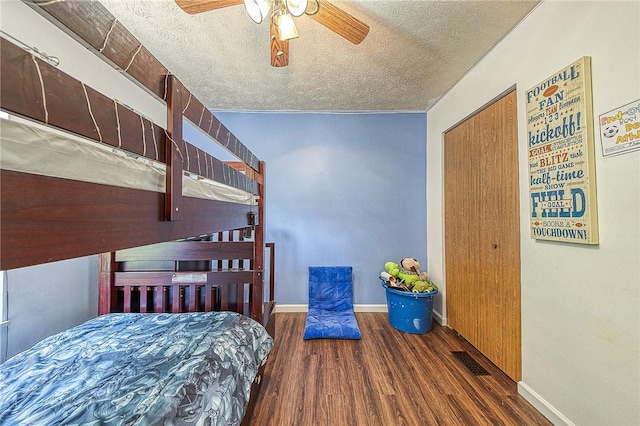 bedroom with a textured ceiling, dark wood-type flooring, a ceiling fan, visible vents, and baseboards