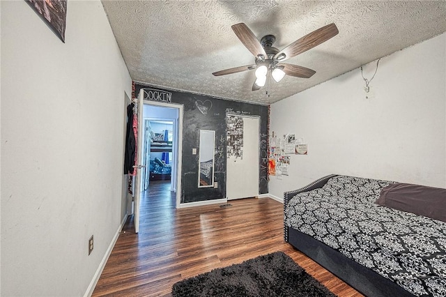 bedroom with dark wood-style floors, a ceiling fan, baseboards, and a textured ceiling