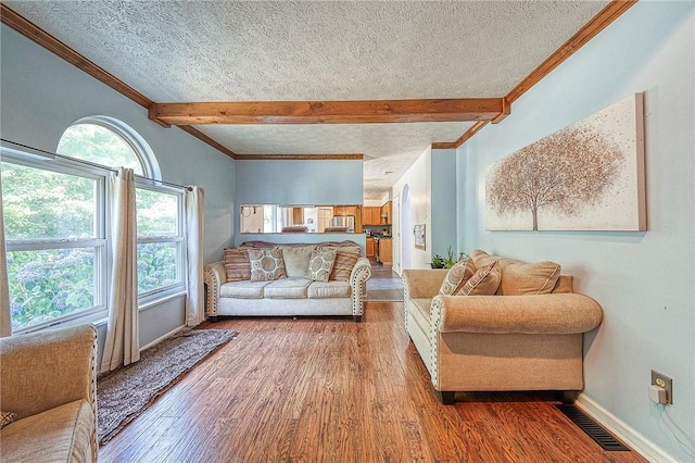 living area with a textured ceiling, visible vents, and beam ceiling