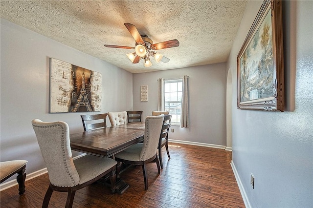 dining area with dark wood-style floors, a textured ceiling, baseboards, and a ceiling fan