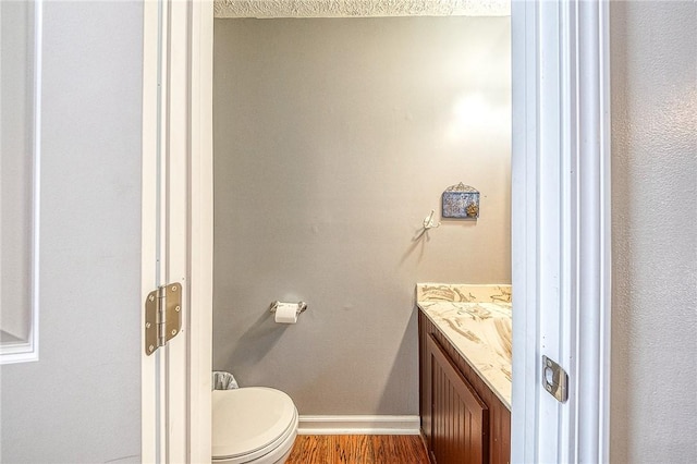 bathroom featuring vanity, wood finished floors, toilet, and baseboards