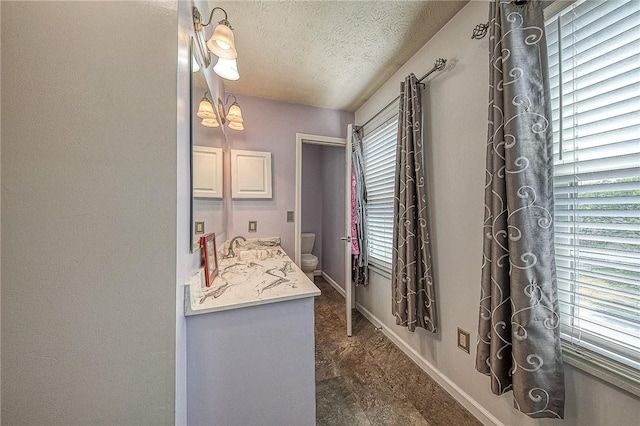 bathroom featuring a textured ceiling, plenty of natural light, toilet, and baseboards