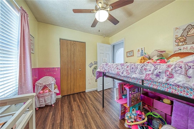 bedroom with dark wood finished floors, a textured ceiling, baseboards, and ceiling fan