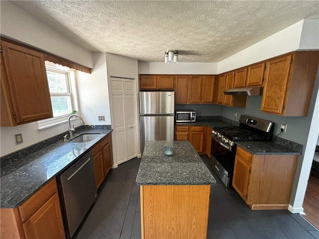 kitchen featuring stainless steel appliances, under cabinet range hood, a sink, and brown cabinets