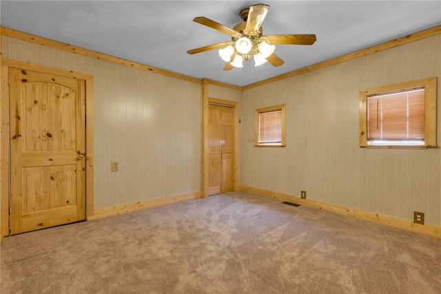 carpeted spare room featuring a healthy amount of sunlight, crown molding, and ceiling fan