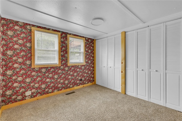 unfurnished bedroom with carpet floors and two closets