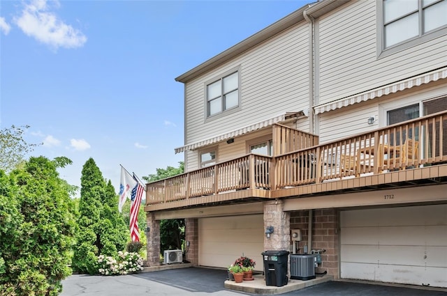 back of property with a garage, driveway, central air condition unit, and cooling unit