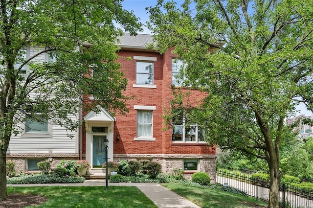 multi unit property featuring a front yard, fence, and brick siding