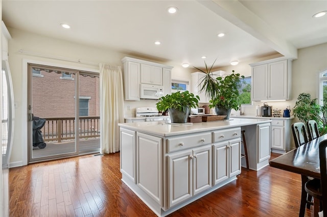 kitchen featuring a center island, white appliances, light countertops, and dark wood finished floors