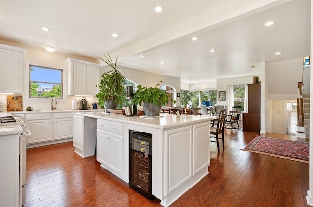 kitchen with wine cooler, stove, light countertops, a center island, and dark wood finished floors