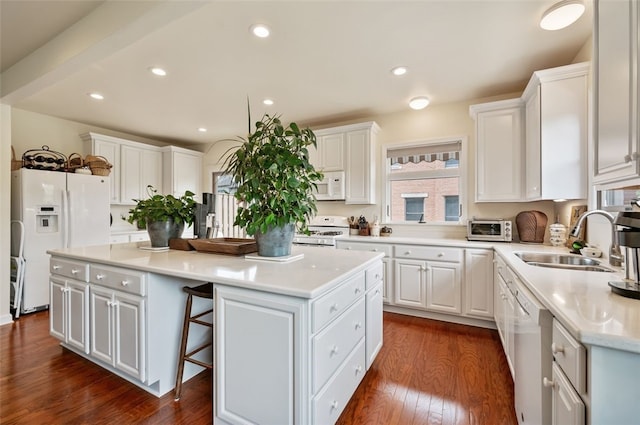 kitchen featuring white appliances, a sink, a kitchen island, white cabinets, and dark wood-style floors