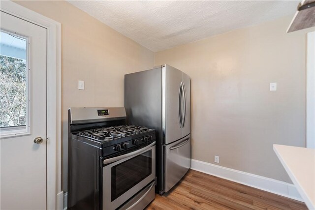 kitchen featuring a healthy amount of sunlight, stainless steel appliances, a textured ceiling, and light wood-type flooring