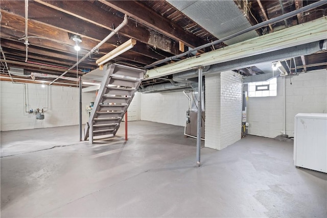 basement featuring refrigerator, heating unit, and water heater