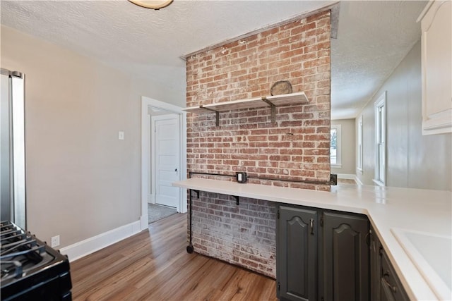 kitchen featuring dark brown cabinets, a textured ceiling, sink, light hardwood / wood-style flooring, and range