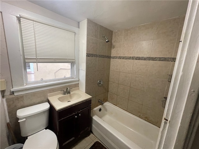 full bathroom featuring tile walls, tiled shower / bath, vanity, toilet, and tile patterned floors