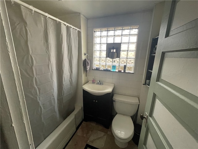 full bathroom with tile walls, tile patterned flooring, shower / bath combo with shower curtain, vanity, and toilet