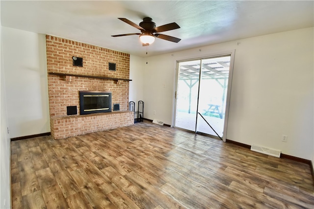 unfurnished living room with ceiling fan, a fireplace, and wood-type flooring