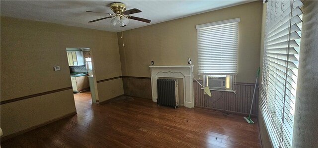 unfurnished living room featuring cooling unit, ceiling fan, radiator heating unit, and dark hardwood / wood-style flooring