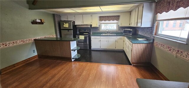 kitchen with sink, white cabinetry, tasteful backsplash, stainless steel appliances, and hardwood / wood-style floors